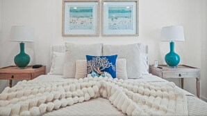 Una camera da letto con un letto, due comodini, due lampade, una coperta e due quadri appesi al muro.
