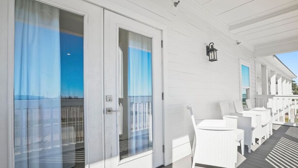 A covered outdoor area with white wicker furniture and a view of the sea. - Extended Stay Friendly-Full Kitchen & Laundry (Pass Christian)