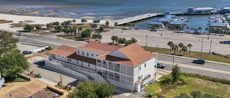 A coastal building with a two-story structure, a covered parking area, and a marina with boats.
