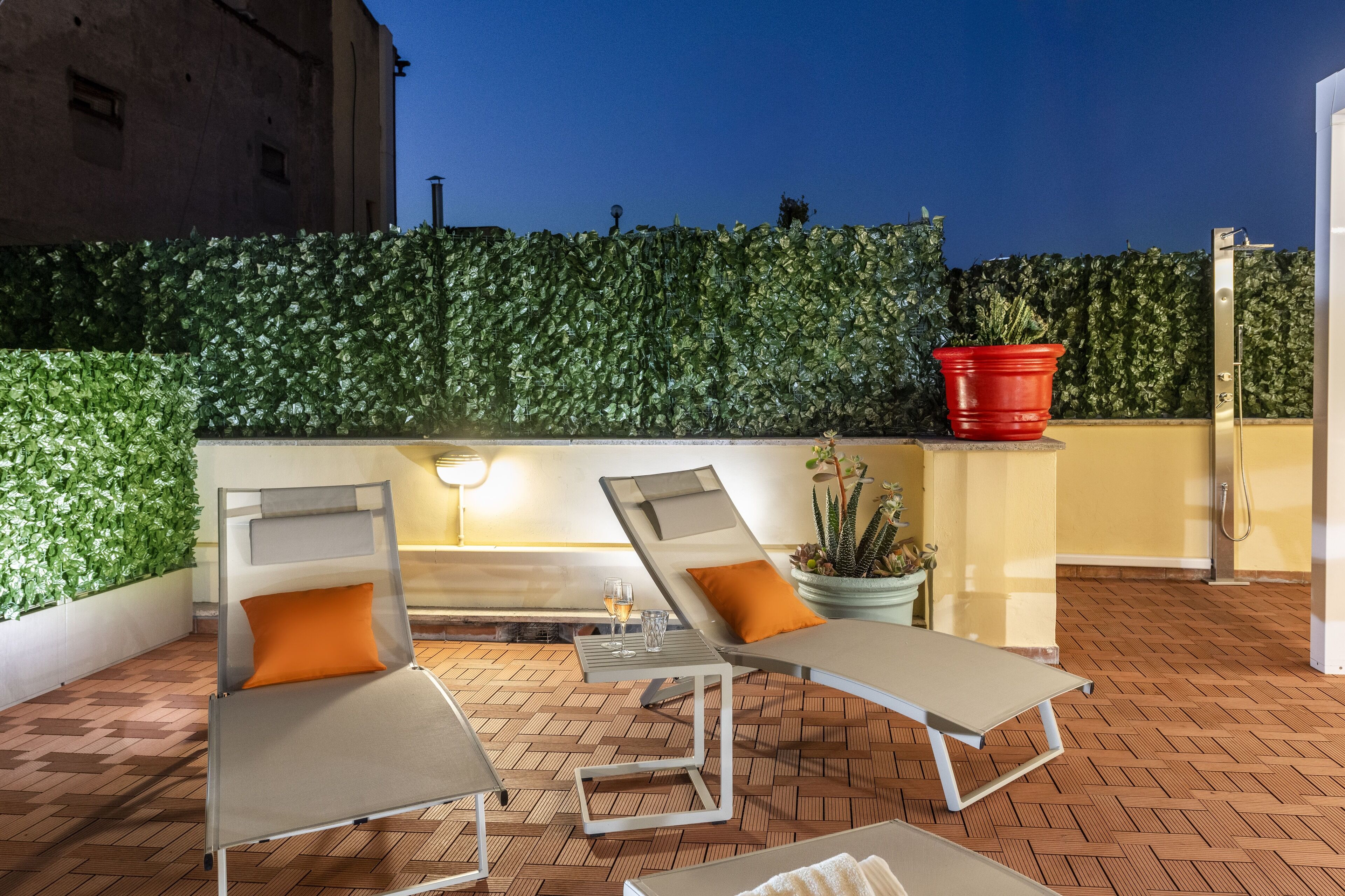 Une terrasse sur le toit avec deux chaises longues, une petite table et un pot de fleurs.