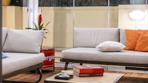 A modern living room with a sofa, a coffee table with a book and a cup, and a potted plant. - Cestari Luxury Terraces (Rome)