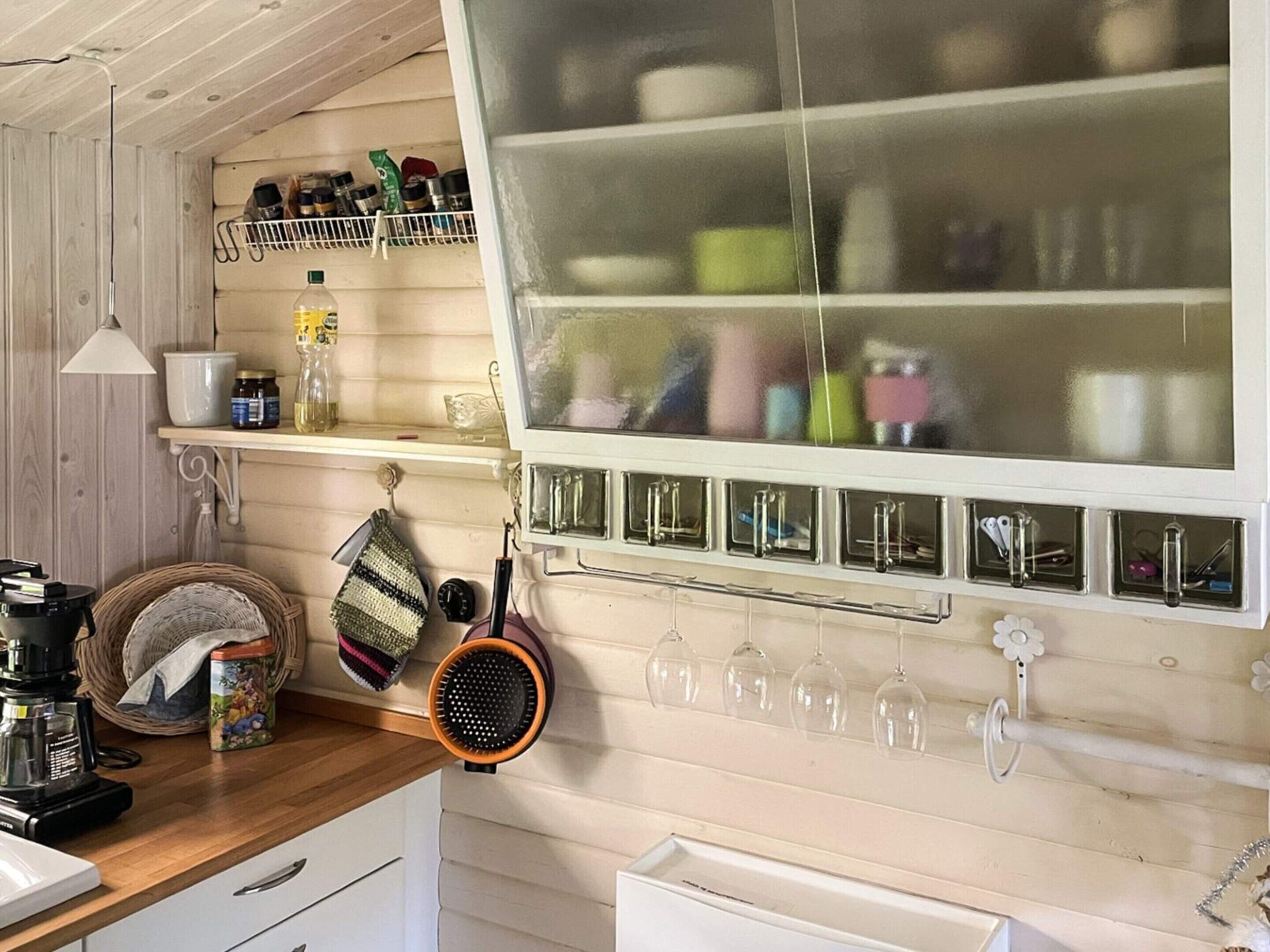 Una cocina con armarios de madera, un perchero con utensilios de cocina y una ventana con vistas al exterior.