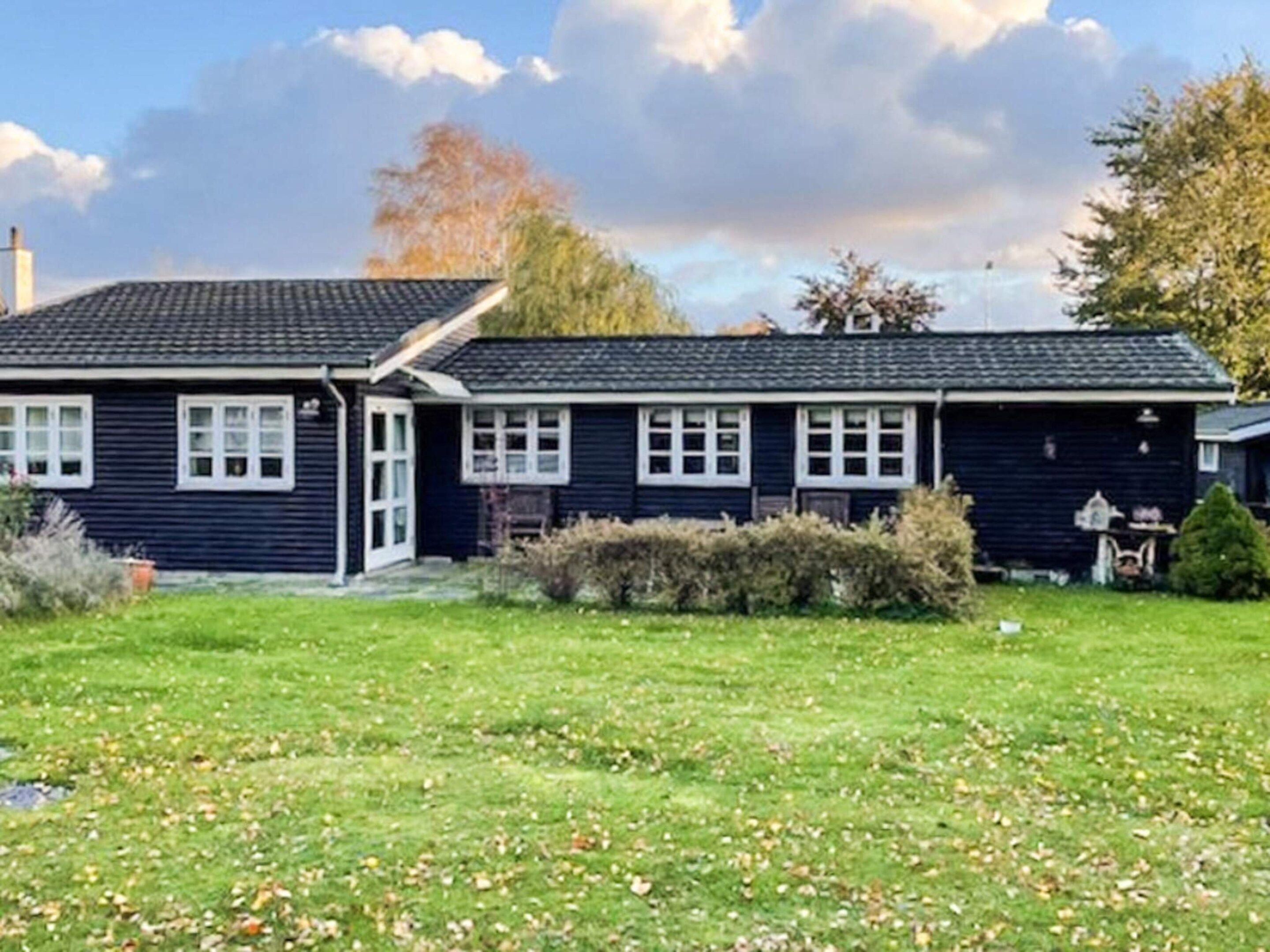 A two-story house with a dark exterior, a front porch, and a well-maintained lawn.