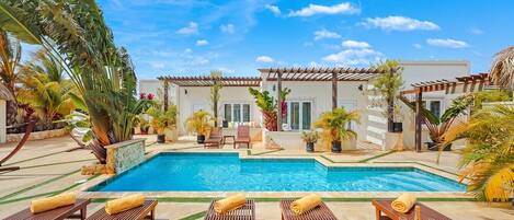 A pool area with lounge chairs and a building in the background.