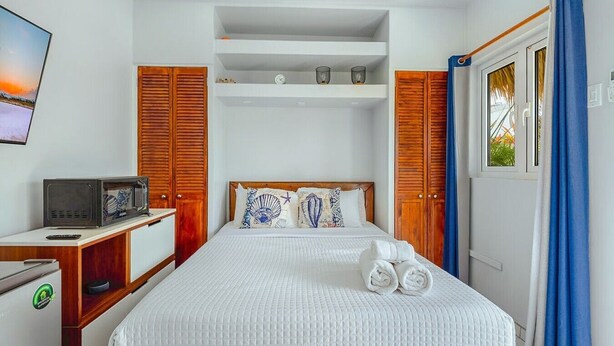 A hotel room with a bed, a television, a desk, and a wardrobe. - EVA Boutique Resort & SPA | The Dushi Studio (Savaneta)