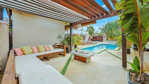 A covered outdoor seating area with a pool and greenery. - EVA Boutique Resort & SPA | The Dushi Studio (Savaneta)