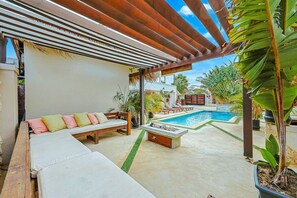 A covered outdoor seating area with a pool and greenery. - EVA Boutique Resort & SPA | The Dushi Studio (Savaneta)