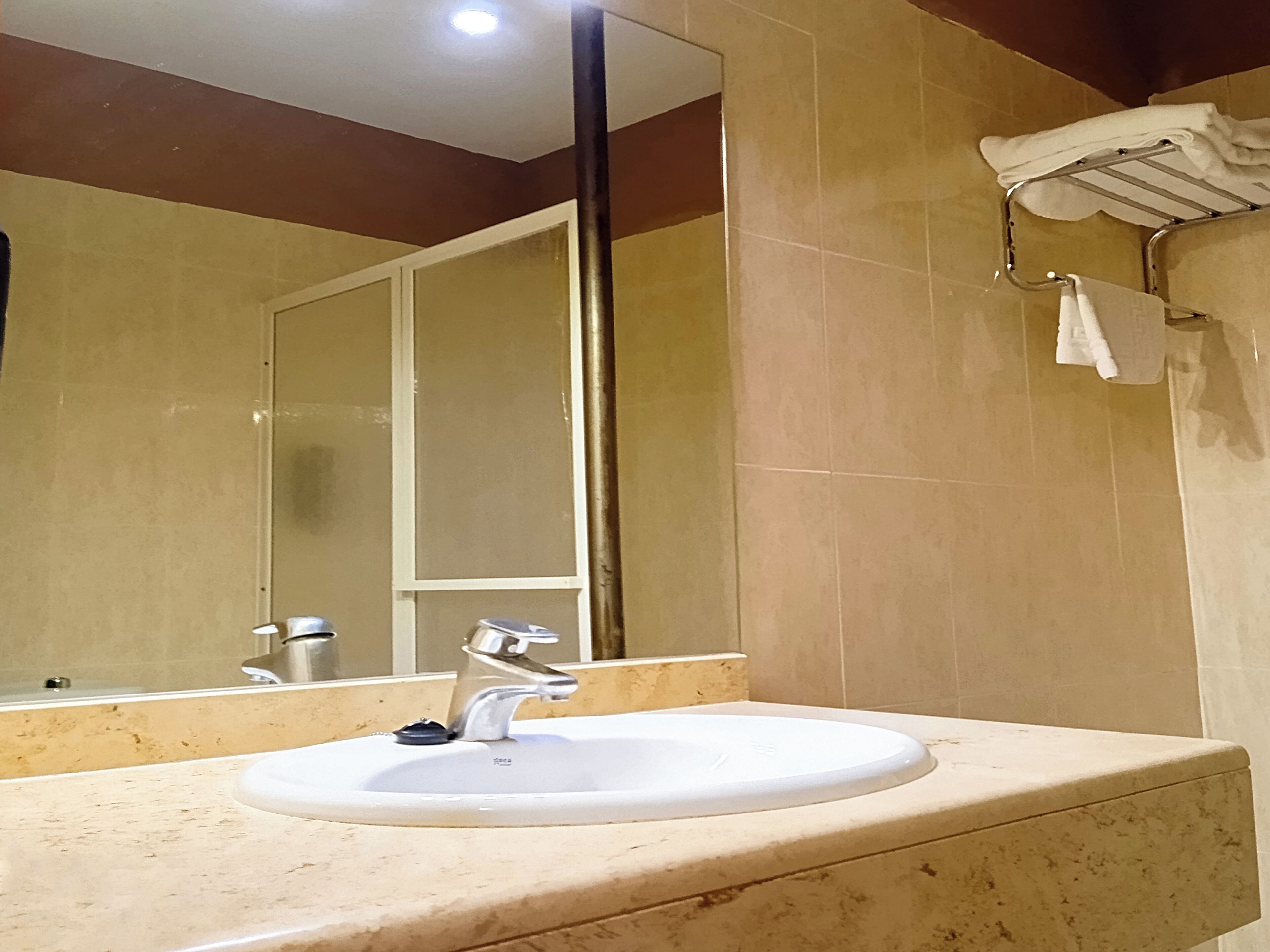 A bathroom with a white sink, a mirror, and a towel rack.