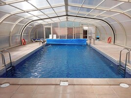 Una piscina interior con techo de cristal, suelo de baldosas y boyas salvavidas.