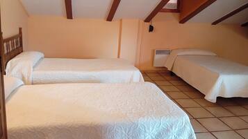 A room with two beds, wooden beams on the ceiling, and a wall-mounted heater.