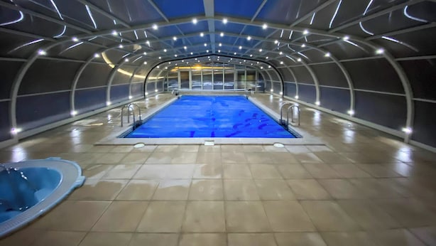 Une piscine intérieure dotée d’un plafond incurvé et d’un sol carrelé.