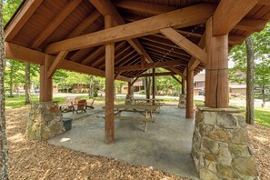 A covered picnic area with stone pillars, wooden benches, and picnic tables. - New! Ski In/Ski Out Home w/ Hot Tub & Fireplace (McHenry)