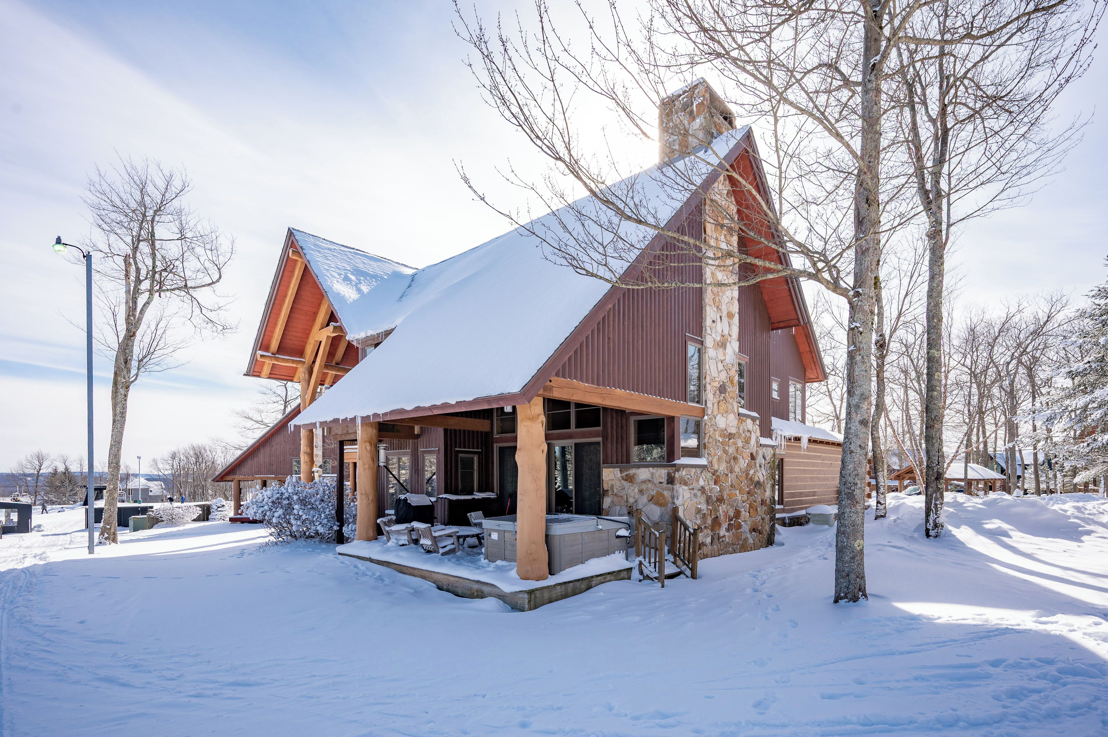 A snow-covered lodge with a stone exterior, wooden beams, and a large chimney.