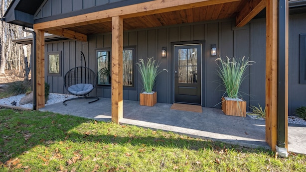 Een modern huis met een overdekte veranda, een hangstoel en twee potplanten.