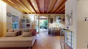 A cozy living room with a sofa, a dining area with chairs and a table, and a kitchen with a counter and cabinets. - Borgo Torchio F1 By Bookinggardalake (Manerba del Garda)
