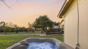 Un jacuzzi dans un jardin, avec une maison en arrière-plan.