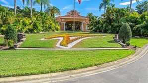 A building with a red roof, surrounded by palm trees and a well-maintained lawn with a geometric design. - Lakefront Terra Verde Retreat Near Disney (Kissimmee)
