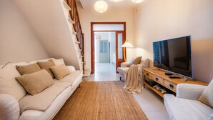 A modern living room with a sofa, TV, and wooden entertainment unit. - Ca'n Ruquet – Your Mallorcan Hideaway in the Heart of Campanet (Campanet)