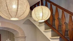 A staircase with wooden balusters, a beige sofa with brown cushions, and a dining area with white chairs and a table. - Ca'n Ruquet – Your Mallorcan Hideaway in the Heart of Campanet (Campanet)