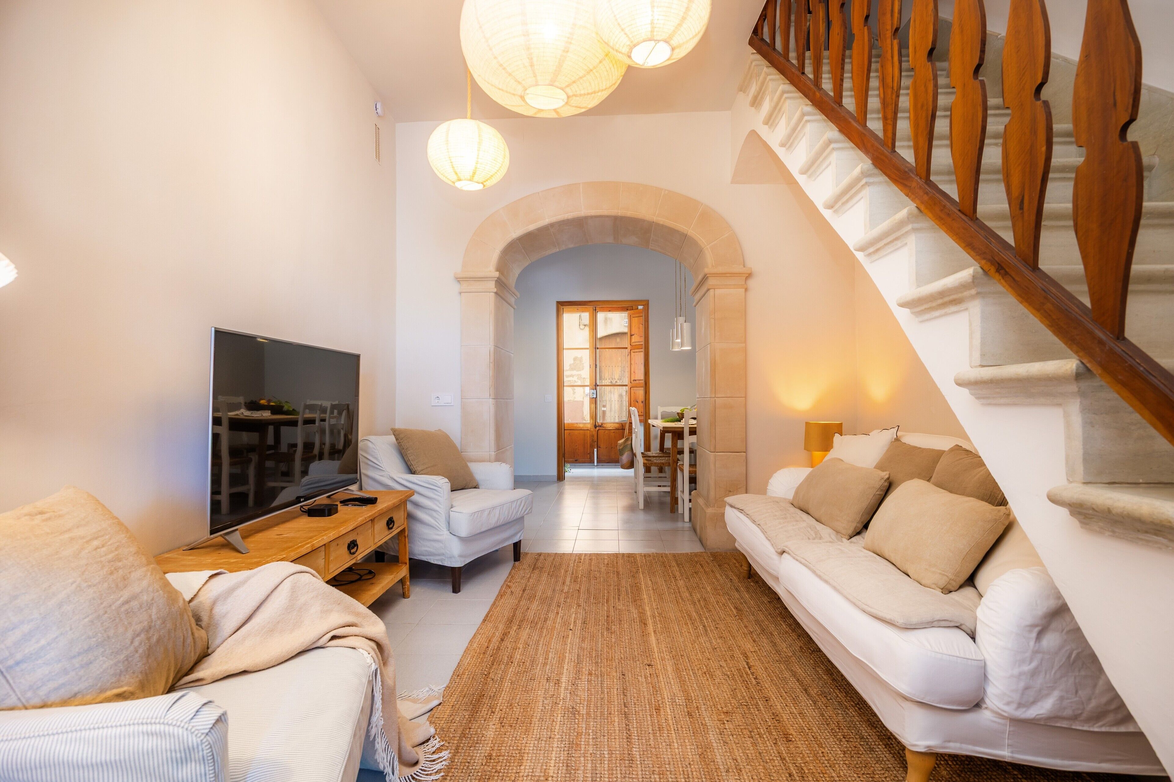 Una sala de estar con televisión, dos sofás, una mesa de centro y una escalera.