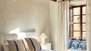 A bedroom with a bed, pillows, a bedside lamp, a window with curtains, and a ceiling fan. - Ca'n Ruquet – Your Mallorcan Hideaway in the Heart of Campanet (Campanet)