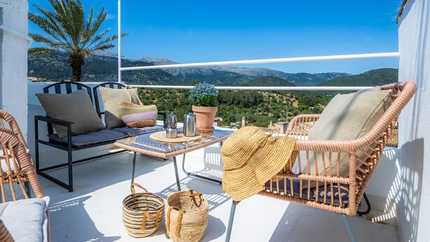 A balcony with wicker furniture, a table with a plant, and a view of mountains. - Ca'n Ruquet – Your Mallorcan Hideaway in the Heart of Campanet (Campanet)