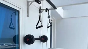 En balkon med en pull-up stang, en vægtstang og røde stole.