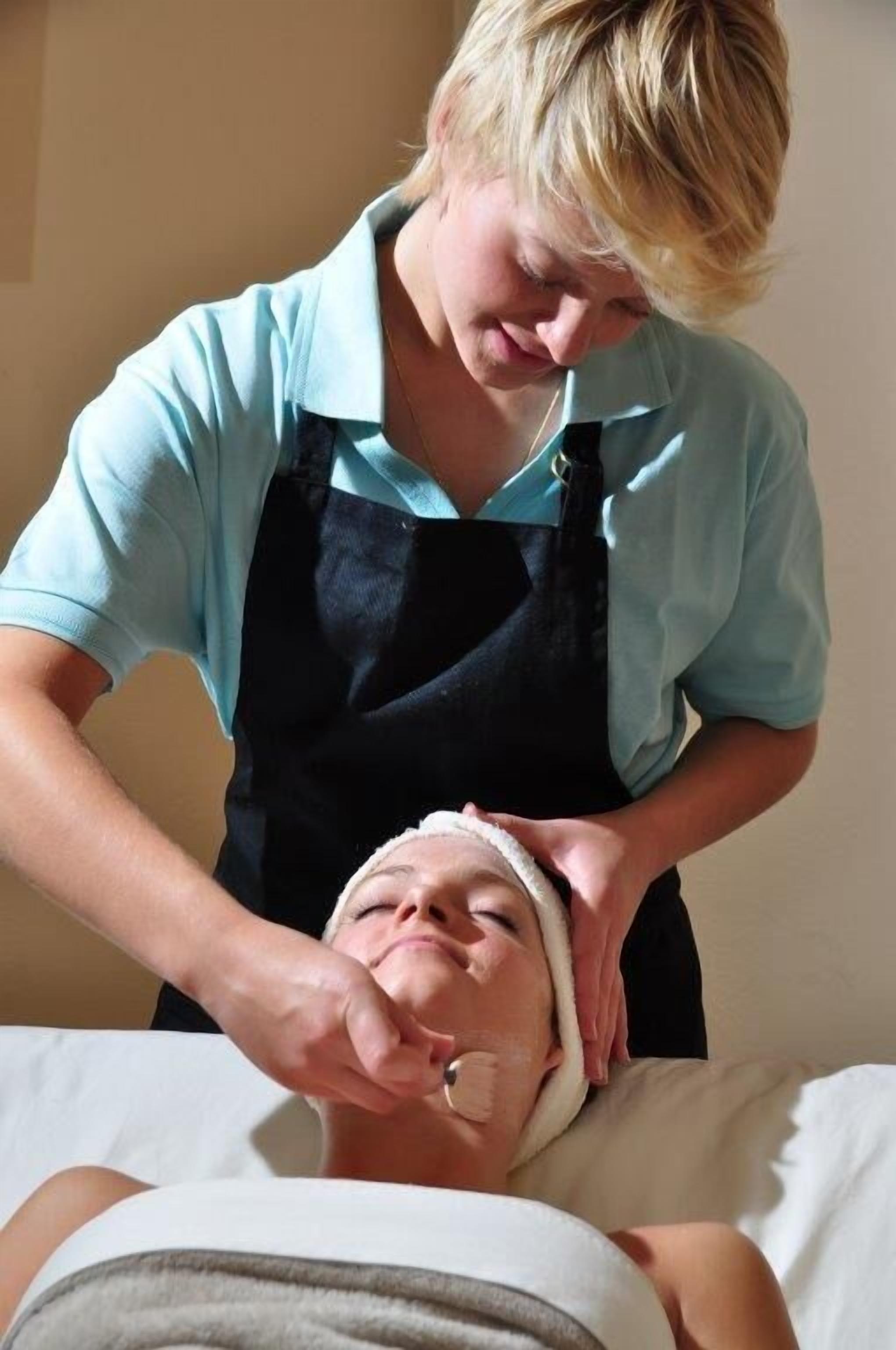 Une personne allongée sur un lit en train de recevoir un soin du visage.