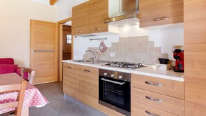 Una cocina moderna con armarios de madera, una estufa a gas, un horno y un comedor con mesa y sillas.