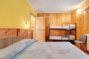 Une chambre avec un lit superposé, un lit simple et une chaise.