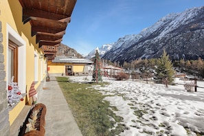 Ein Gebäude mit Holzfassade, einem mit Schnee bedeckten Rasen und einer Bergkulisse.