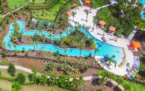 An aerial view of a resort with a winding pool, palm trees, and lounge areas. - 5‑BR Villa w/ Private Pool & Spa near Disney (Davenport)