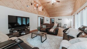 A spacious living room with a wooden ceiling, leather sofas, a flat-screen TV, and a ceiling fan. - Cozy 3-bedroom cabin with a spacious wrap around deck located in landisburg pa (Landisburg)