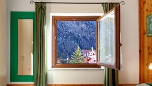 Ein Schlafzimmer mit einem hölzernen Bett, einem Fenster mit Blick auf einen Wald und einer grünen Tür.