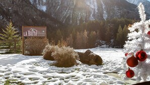 Ein Schild für 'La Baite Casa Appartamenti' in einer verschneiten Berglandschaft mit Blick auf die Berge.