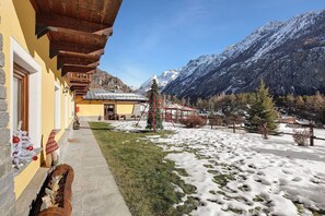 Un bâtiment doté d’un balcon en bois, d’une pelouse recouverte de neige et ayant une chaîne de montagnes en toile de fond.
