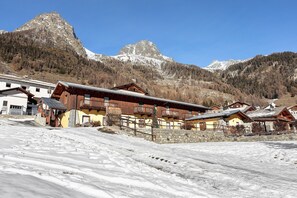A mountain village with wooden buildings, a snow-covered slope, and a prominent mountain peak in the background. - Apartment 'L'Achillea' with Lake View and Wi-Fi (Bionaz)