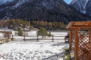 A snow-covered landscape with a wooden gazebo, a fenced area, and a mountain backdrop. - Apartment 'La Viola' with Lake View and Wi-Fi (Bionaz)