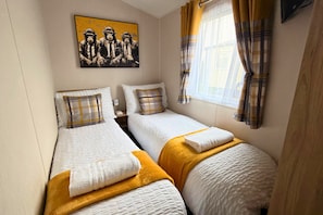 Een kamer met twee bedden, een schilderij aan de muur en een raam met gordijnen.