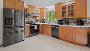 Una cocina moderna con electrodomésticos de acero inoxidable, armarios de madera y un amplio ventanal que proporciona luz natural.
