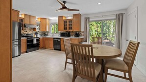 Una cocina moderna con armarios de madera, electrodomésticos de acero inoxidable y un comedor con sillas de madera.