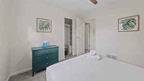 Un dormitorio con cama, cómoda, armario y ventilador de techo.