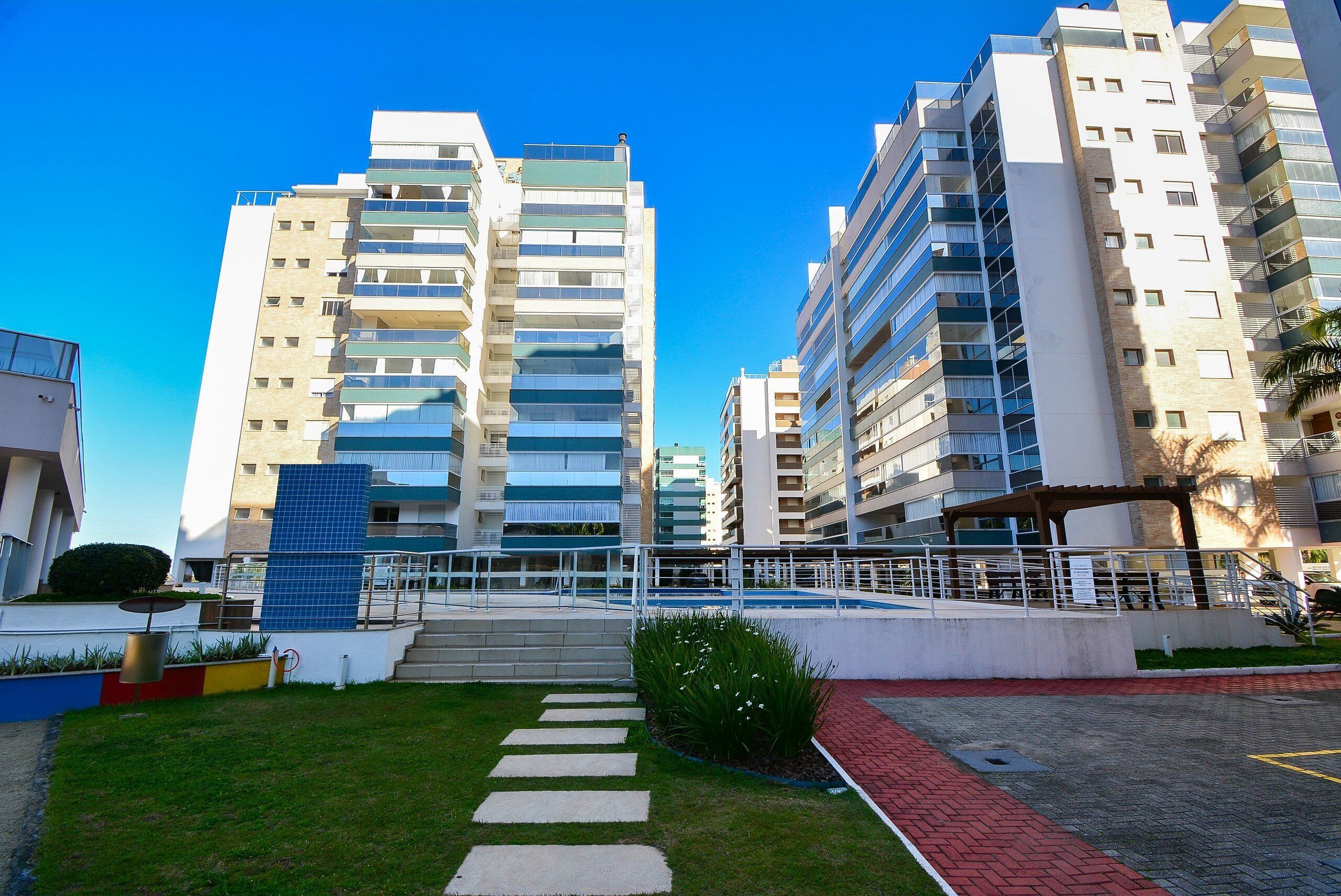Un edificio de apartamentos moderno con varios pisos, balcones y un patio central con un sendero.