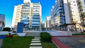 Un edificio de apartamentos moderno con varios pisos, balcones y un patio central con un sendero.