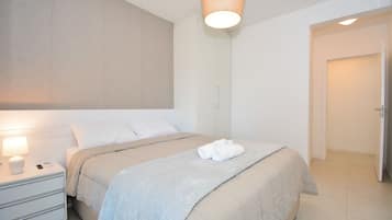 Un dormitorio moderno con cama, mesita de noche y lámpara colgante.