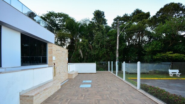 Un edificio moderno con una terraza de madera, una pared exterior blanca y un ventanal de vidrio.