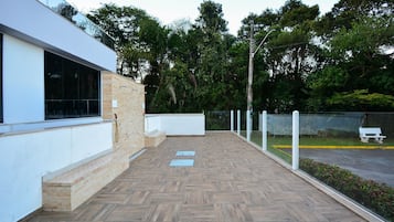 Un edificio moderno con una terraza de madera, una pared exterior blanca y un ventanal de vidrio.