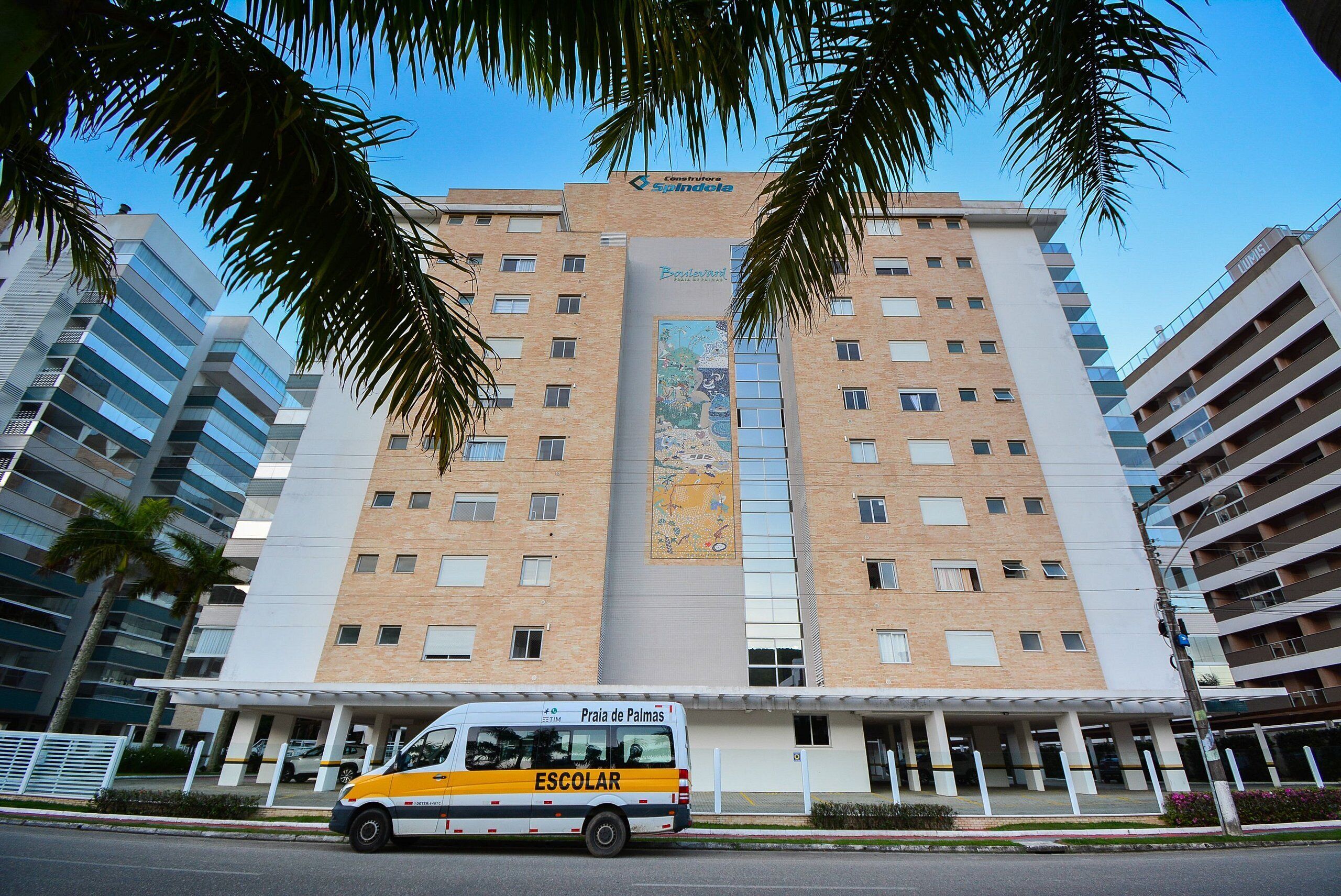 A multi-story building with a central entrance and a bus in front.
