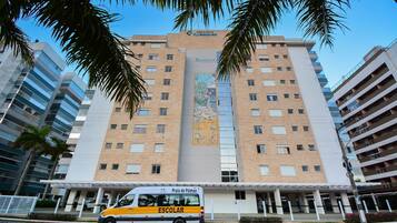 A multi-story building with a central entrance and a bus in front.