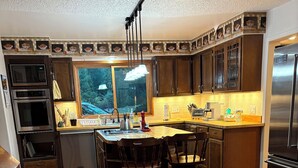Een keuken met donkere houten kasten, een roestvrijstalen koelkast en een betegelde vloer.